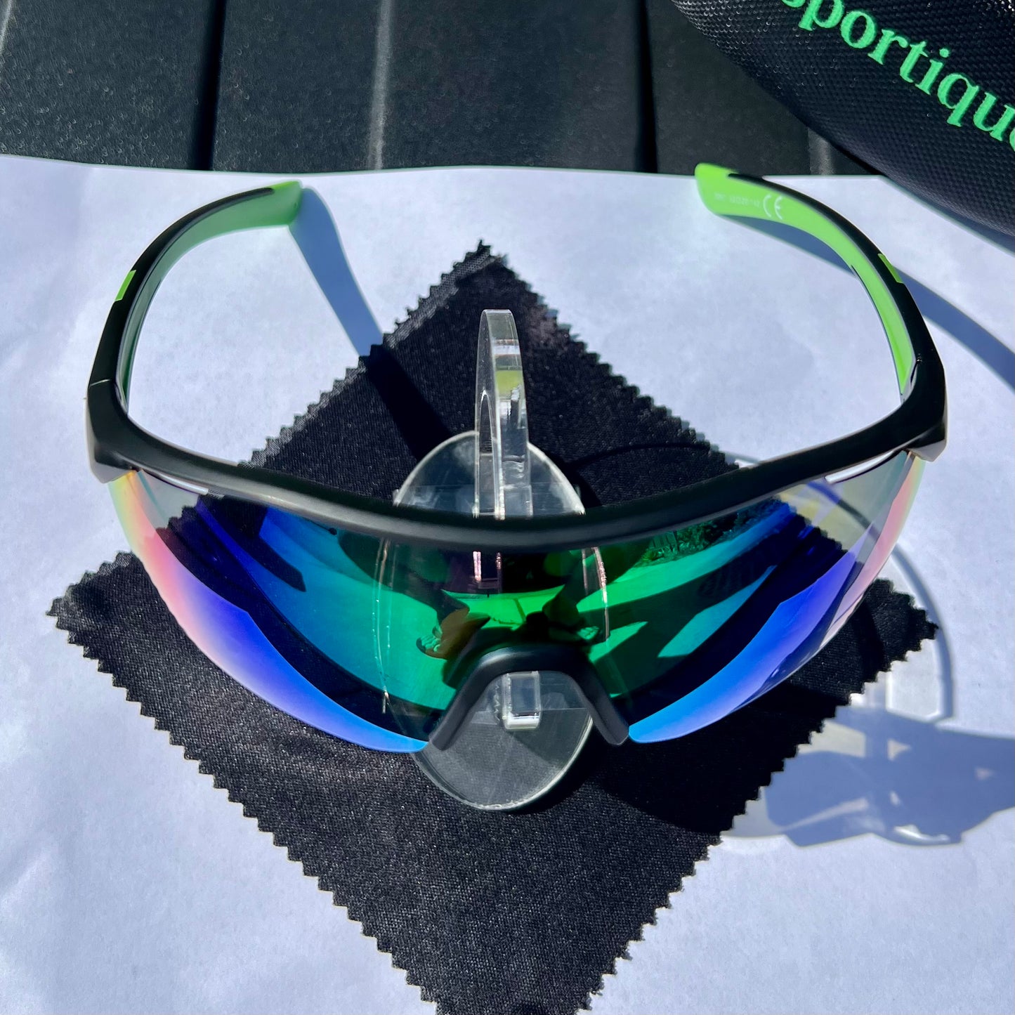 A pair of Sportiq ClarityX - Emerald professional sport sunglasses with green reflective lenses and black frame, polarized UV400, polycarbonate frame with TAC lens, displayed on a grass background.