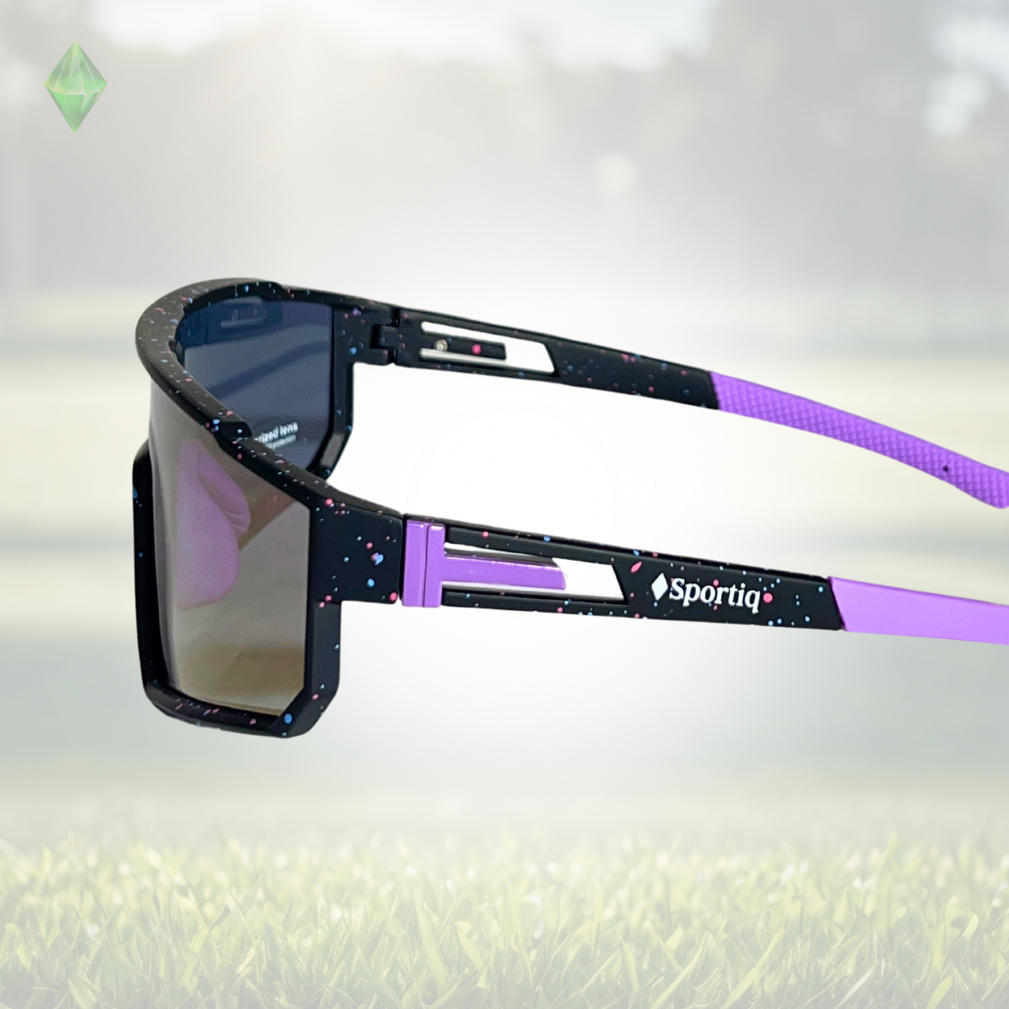 A pair of Sportiq VividShield sunglasses with a purple reflective lens and black frame, polarized UV400, polycarbonate frame with TAC lens, displayed on a grass background.