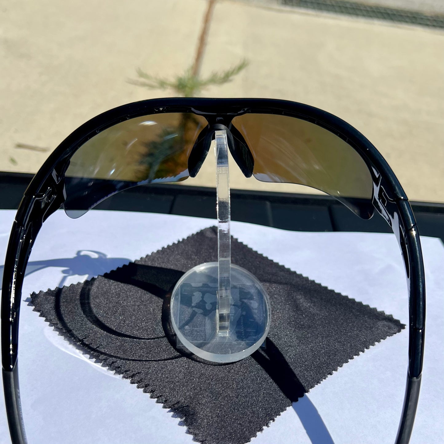 A pair of Sportiq OptiView - Sky Blue professional sport sunglasses with blue reflective lenses and black frame, polarized UV400, polycarbonate frame with TAC lens, displayed on a grass background.