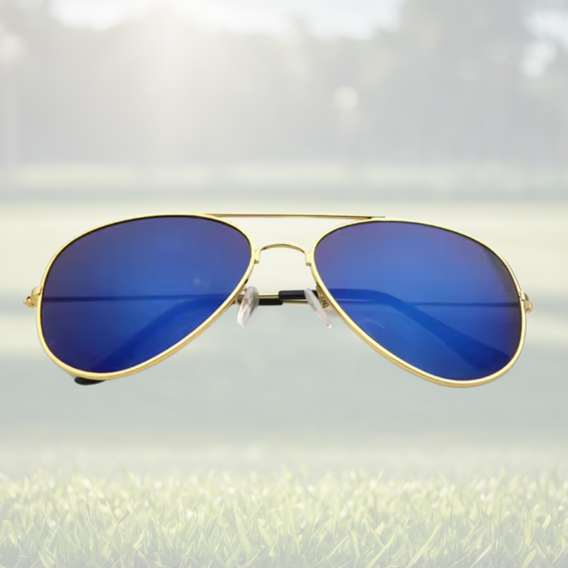 A pair of Sportiq Altitude Royal performance sunglasses with blue lenses and steel frame, UV400 rate with a polycarbonate lens, displayed on a grass background.