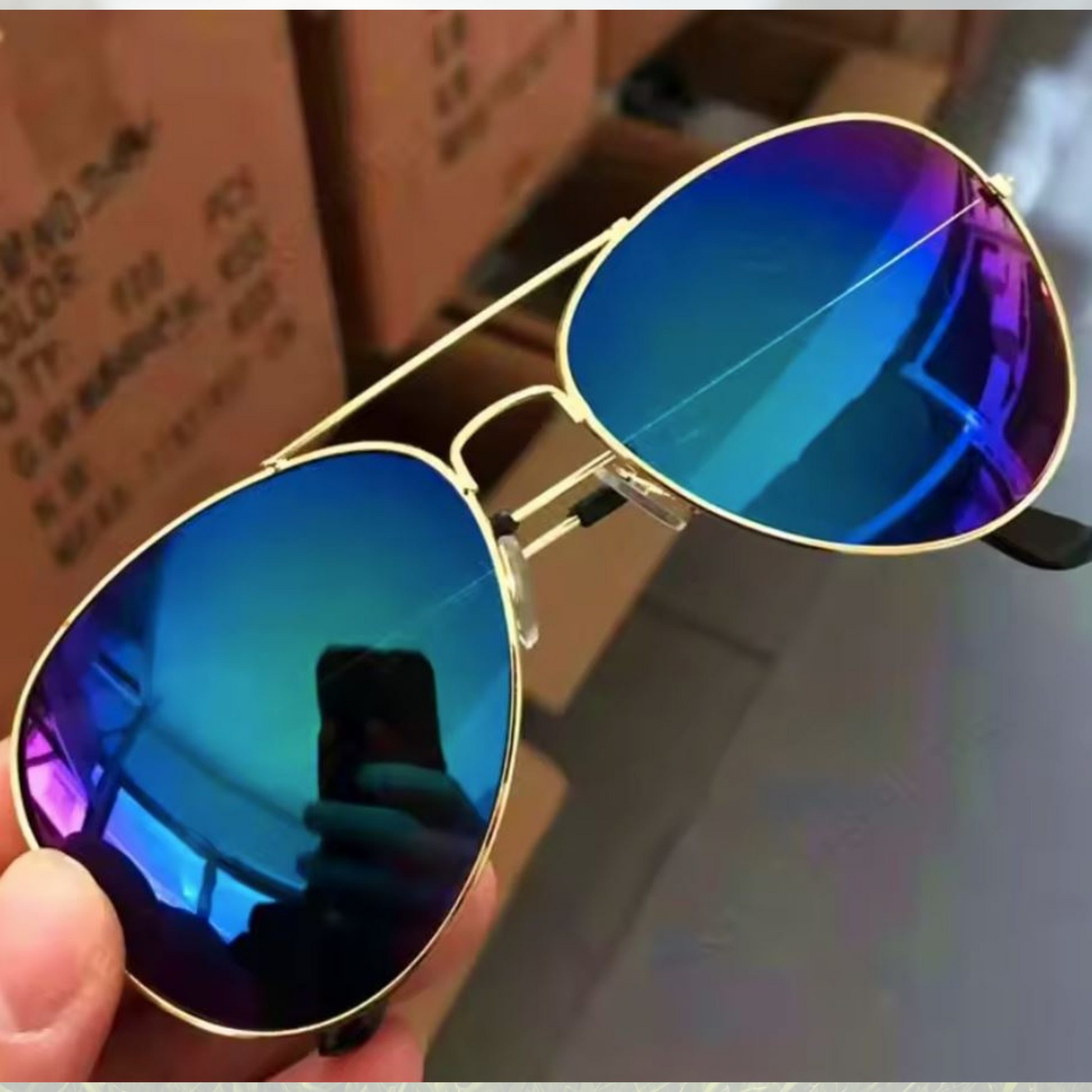 A pair of Sportiq Altitude Royal performance sunglasses with blue lenses and steel frame, UV400 rate with a polycarbonate lens, displayed on a grass background.