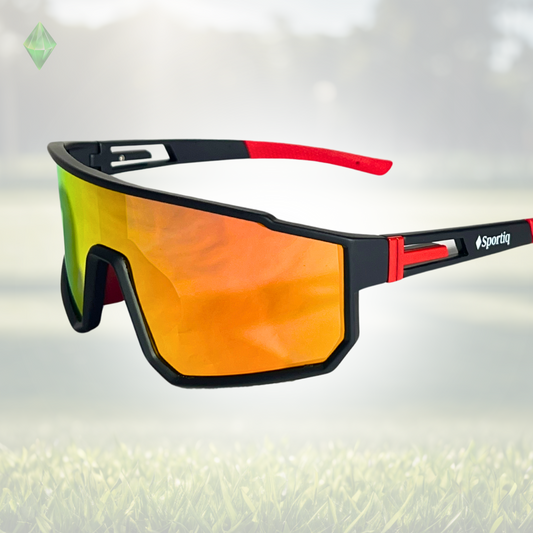 A pair of Sportiq VividShield sunglasses with black and red frame and red reflective lens, polarized UV400, polycarbonate frame with TAC lens, displayed on a grass background.