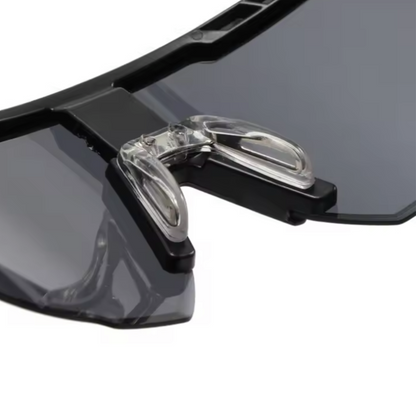 A pair of Sportiq Nimbus Flare performance sunglasses with red reflective lenses and black frame, UV400, polycarbonate frame with polycarbonate lens, displayed on a grass background.