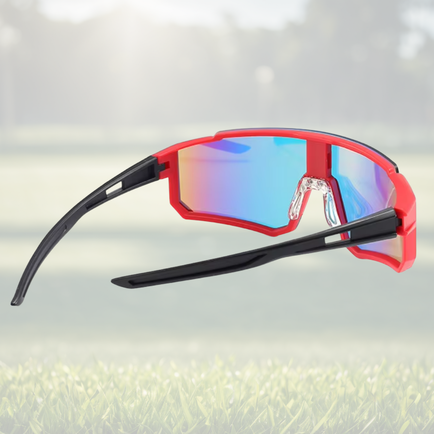 A pair of Sportiq Velocity Blaze performance sunglasses with red reflective lenses and black frame, UV400, polycarbonate frame with polycarbonate lens, displayed on a grass background.