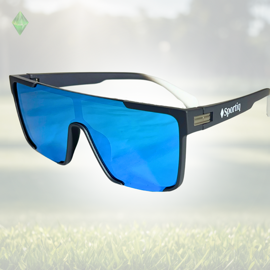A pair of Sportiq Zen - Blue professional sport sunglasses with blue reflective lenses and black frame, polarized UV400, polycarbonate frame with TAC lens, displayed on a grass background.