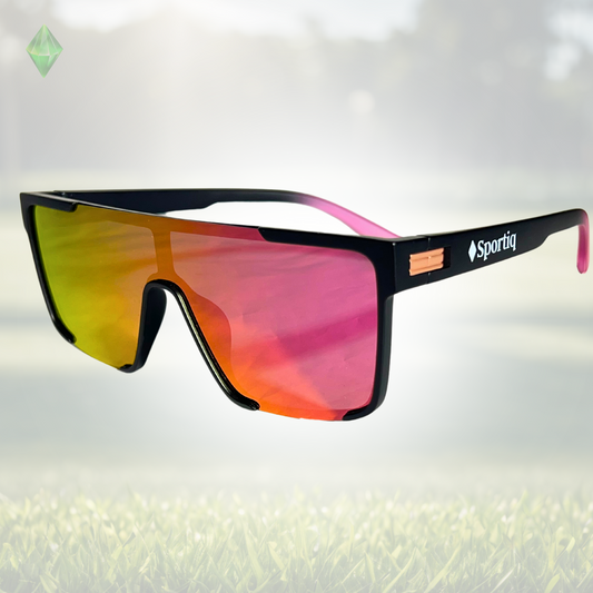 A pair of Sportiq Zen - Pink professional sport sunglasses with pink reflective lenses and black frame, polarized UV400, polycarbonate frame with TAC lens, displayed on a grass background.